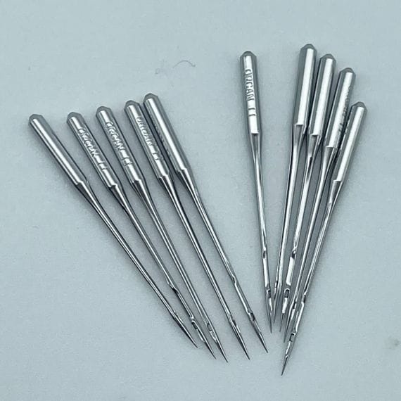 Macro close-up photograph of a sewing machine needle showing the eye, shaft, and tip