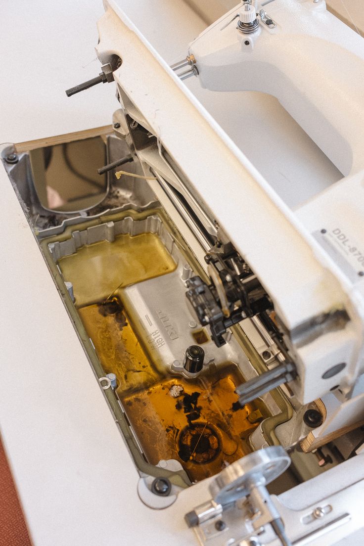 Close-up photograph of an industrial sewing machine oil reservoir window showing the oil level indicator