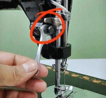 Close-up photograph of a sewing machine presser foot lever in the raised position
