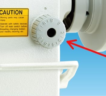 Close-up photograph of a sewing machine stitch length dial or lever showing the numbered scale
