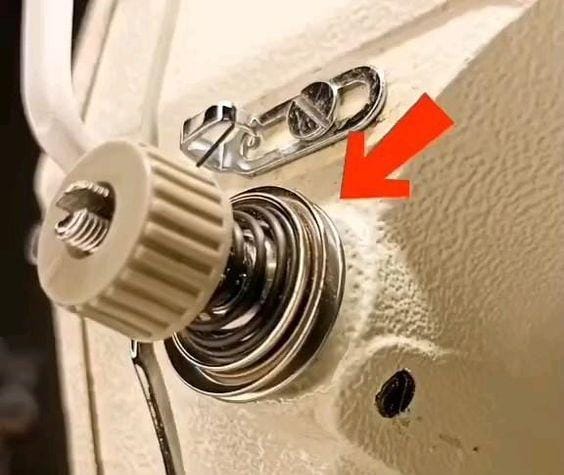 Close-up photograph of a sewing machine tension dial on the machine face, which controls the internal tension discs