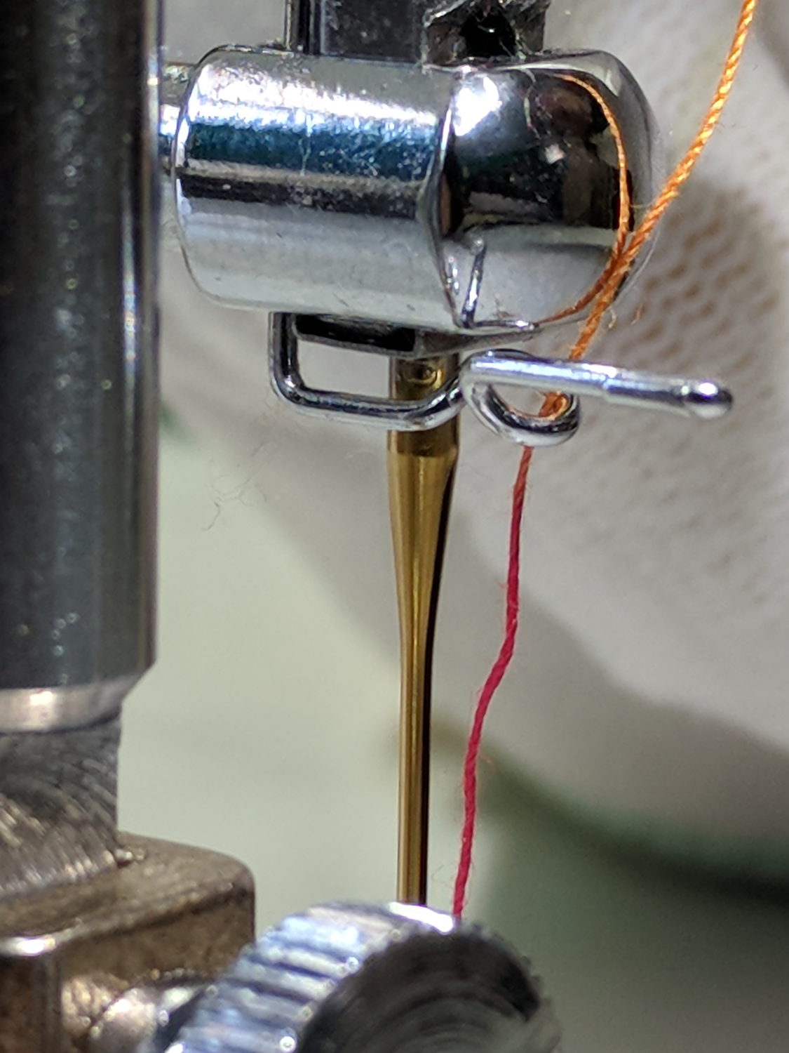 Close-up photograph of sewing machine thread guides showing the threading path from spool to needle